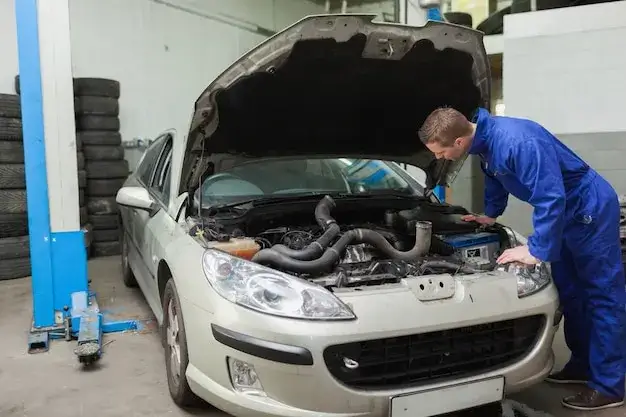 Samochód z otwartą maską i mechanik sprawdzający sprzęgło