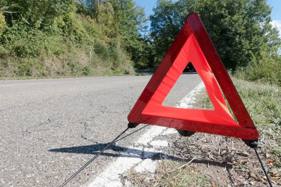 Zabezpieczony samochód na pasie awaryjnym autostrady z trójkątem ostrzegawczym